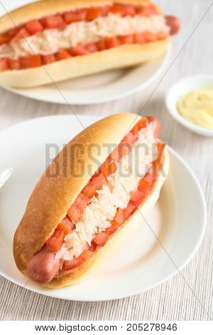 Chilean Completo Clasico (classical) or Completo Aleman (German) traditional hot dog sandwiches made of bread sausage tomato cubes and sauerkraut photographed with natural light (Selective Focus Focus one third into the first hotdog)