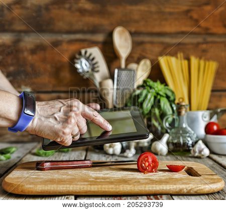 Concept: Cooking In The Kitchen In The Restaurant. The Cook Is Holding A Tablet Computer