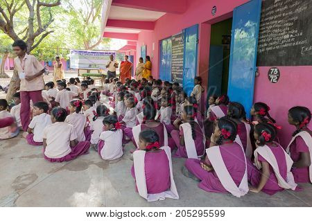 PONDICHERY PUDUCHERY INDIA - SEPTEMBER 04 2017. Outdoor meeting of the children of the school with uniforms sitting on the floor waiting for sport equipments as a gift from an association.