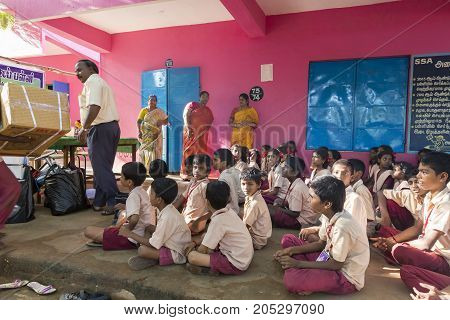 PONDICHERY PUDUCHERY INDIA - SEPTEMBER 04 2017. Outdoor meeting of the children of the school with uniforms sitting on the floor waiting for sport equipments as a gift from an association.