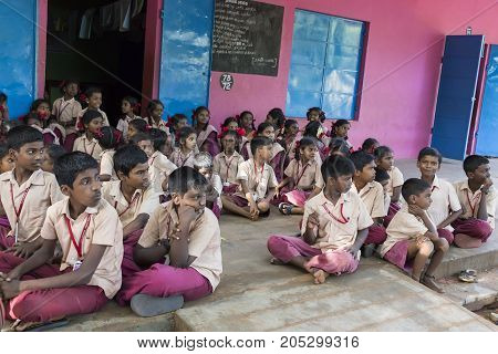 PONDICHERY PUDUCHERY INDIA - SEPTEMBER 04 2017. Outdoor meeting of the children of the school with uniforms sitting on the floor waiting for sport equipments as a gift from an association.