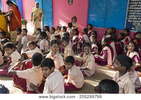 PONDICHERY PUDUCHERY INDIA - SEPTEMBER 04 2017. Outdoor meeting of the children of the school with uniforms sitting on the floor waiting for sport equipments as a gift from an association.