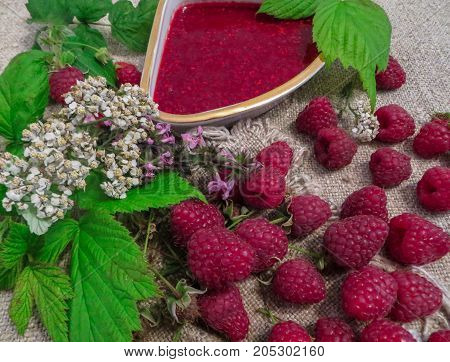 scattered on the table ripe fresh berries of raspberries along with jam.