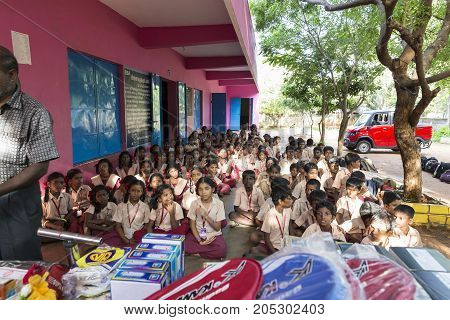 PONDICHERY PUDUCHERY INDIA - SEPTEMBER 04 2017. Outdoor meeting of the children of the school with uniforms sitting on the floor waiting for sport equipments as a gift from an association.