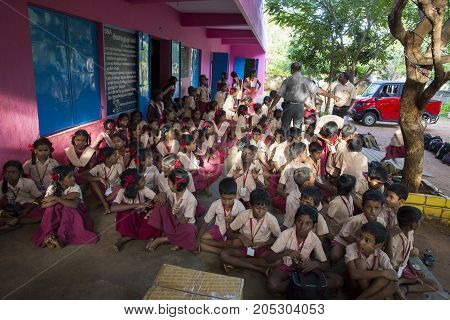 PONDICHERY PUDUCHERY INDIA - SEPTEMBER 04 2017. Outdoor meeting of the children of the school with uniforms sitting on the floor waiting for sport equipments as a gift from an association.
