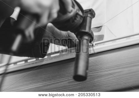 A worker installs panels beige siding on the facade of the house
