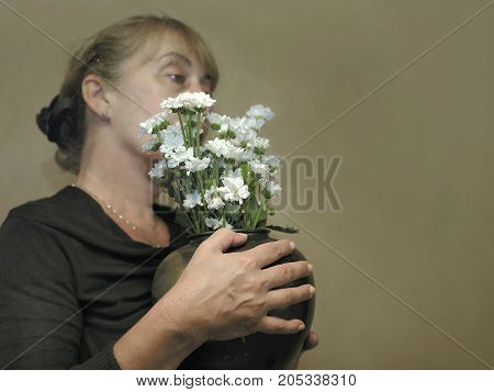 Woman holding a vase with beautiful chrysanthemum. Filterd studio portrait
