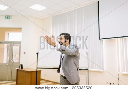 Professional businessman talking on a conference on a blurred office background. Corporate business meetup. Copy space.