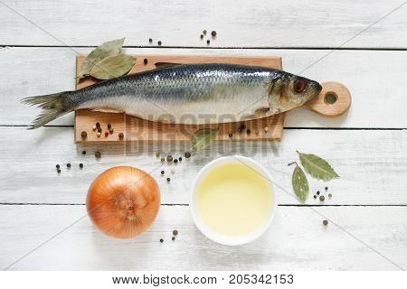 Herring with onions, vegetable oil and spices on a wooden board. The background. Rustic style, selective focus.