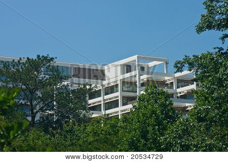 Bílé terasovité kancelářská budova rostoucí stromy do modré oblohy