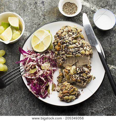 A healthy snack lunch. Baked chicken breast in breaded LSA pumpkin seeds, flax seeds, sunflower seeds, almonds for crispy appetizing crust with radicchio salad, green grapes with basil in a plate on the table. Top View