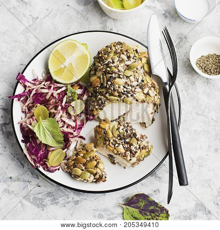A healthy snack lunch. Baked chicken breast in breaded LSA pumpkin seeds, flax seeds, sunflower seeds, almonds for crispy appetizing crust with radicchio salad, green grapes with basil in a plate on the table. Top View