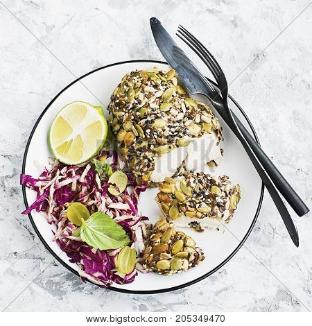 A healthy snack lunch. Baked chicken breast in breaded LSA pumpkin seeds, flax seeds, sunflower seeds, almonds for crispy appetizing crust with radicchio salad, green grapes with basil in a plate on the table. Top View