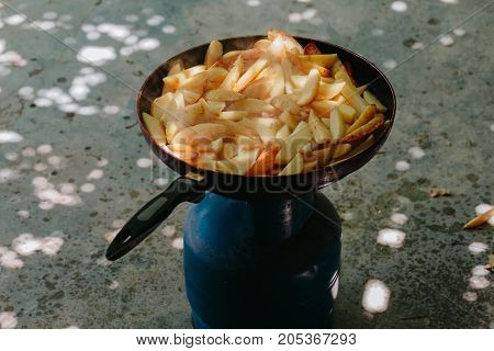 Fried potatoes in a frying pan in the yard on a gas burner