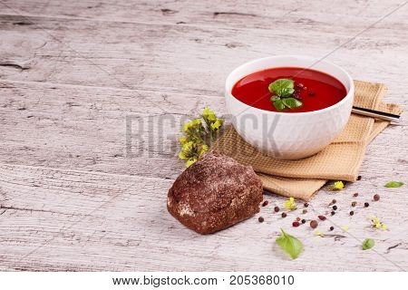 Soup in a bowl with dill, sour cream and black bread on wooden background. National dish of Ukrainian cuisine.