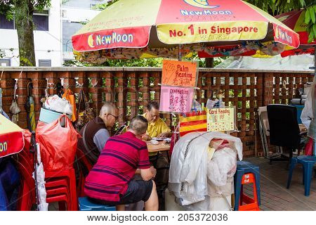 SINGAPORE - SEPTEMBER 7 2017: A fortune teller practices divination for devotees outside the Kwan Im Thong Hood Cho Temple on Waterloo Street in Bugis. The area is a famous haven for fortune tellers.