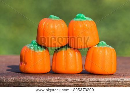Horizontal closeup photo of candy pumpkins in a pyramid shape on wood