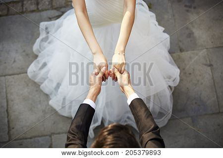 young asian bride and groom holding hands and dancing high angle view.