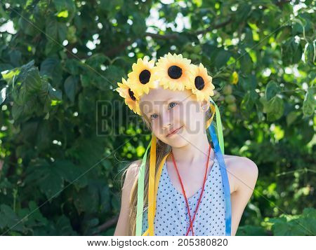 Portrait of beautiful girl with flowers of sunflowers on his head. The concept of a happy carefree childhood.