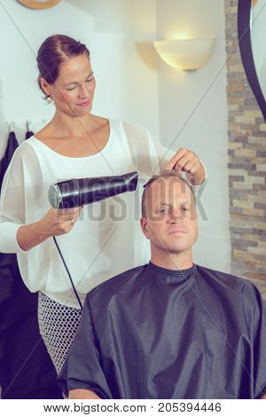 Female Hairdresser Cutting Hair Of Man