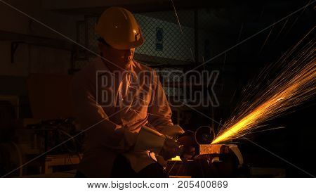 the man worker uses grinding cutting machine to cut metal focus on flash light line of sharp sparkin low Light