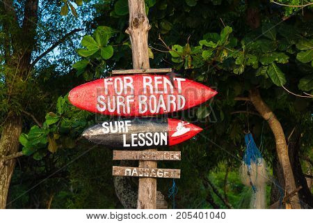 Bali Indonesia - May 12 2017: Sign board advertising surf lessons on Jimbaran beach a main popular balinese attraction famous for the clear blue water and sea food restaurants in Bali Indonesia.