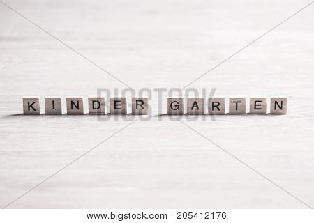 Alphabet letters on wooden pieces collected to word kinder garten