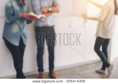 Blurred of Cheerful young student standing holding book and reading classmates helps friend catching up workbook and learning tutoring lean on locker teaching learning Education and school concept.