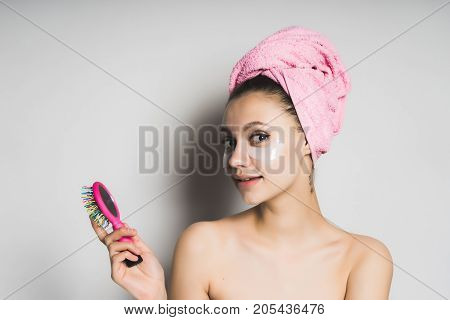 A girl with a mask under her eyes looks in the mirror