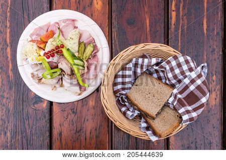 Traditional Brettljausn with bread and a lot of cold cuts on wooden table on south Styrian vine route in Austria