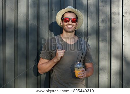 Outdoor Picture Of Young European Male Standing In Sun Hat And Sunglasses With Gray Wooden Fence Beh