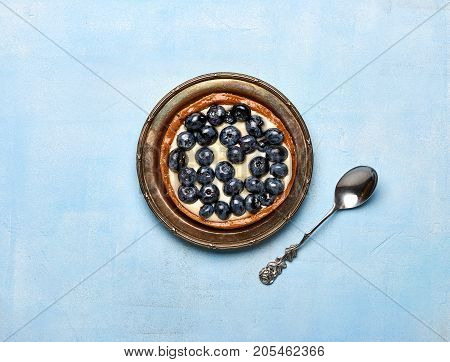 Blueberry tart, pie, tartlet with custard on blue stone background.