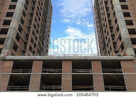 A new house that is being built and a blue sky with light clouds between sections of the house.