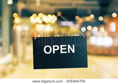 Close up of black open sign hanging on glass door of cafe. Blurry background. Opened concept. 3D Rendering