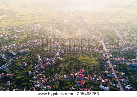 Aerial view of Mukacheve in sunset - a city in the Transcarpathian region, Ukraine. Houses with red roofs against a background of green vegetation in the sun