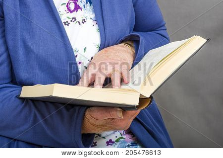 Senior Citizen reading a book.
Close up of a senior citizen reading a hardback book.