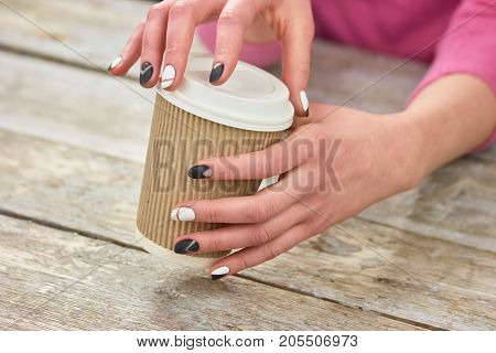 Female hands opening cardboard coffee cup. Young woman hands opening disposable cup with coffee. Time to drink coffee.