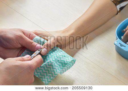 Manicurist cutting the cuticles to client. Beautician trimming cuticles to female client. Woman hands in a nail salon receiving a manicure procedure.
