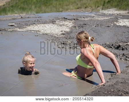 Mother gently bathing my daughter in the mud. Treatment non-traditional methods.