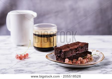 Chocolate flourless brownie cake with berries red currant and cup of coffee on a grey marble table. Healthy breakfast. Selective focus