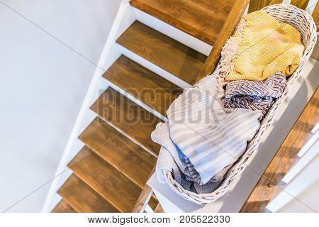 Closeup Of Laundry Or Linen Wooven Basket Filled With Warm Blankets By Stairs Indoors In Staging Mod