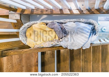 Closeup Of Laundry Or Linen Wooven Basket Filled With Warm Blankets By Stairs Indoors In Staging Mod