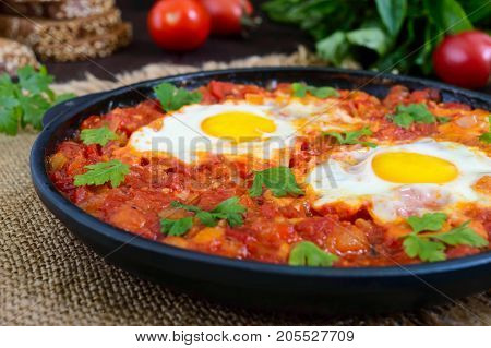Shakshuka - a dish of eggs fried in a sauce of tomatoes hot pepper onions and seasonings. Israeli cuisine. Served for breakfast with rye bread.