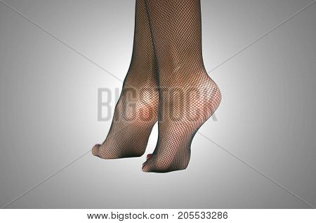 Sexy female legs in fishnet pantyhose stockings standing on toe cap isolated.