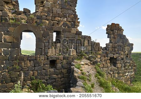 Ruined wall of the medieval armenian fortress Amberd with loopholes and windows