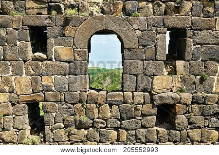 Ruined wall of the medieval armenian fortress Amberd with loopholes and windows