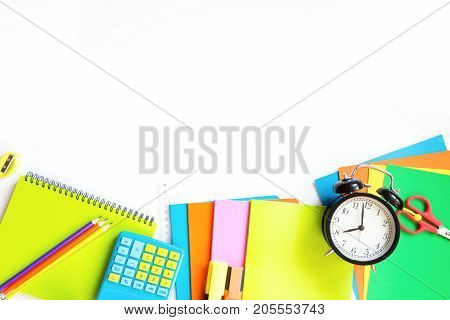 Colorful school supplies, book, and alarm clock on white background. Top view, flat lay. Top view, copy space.