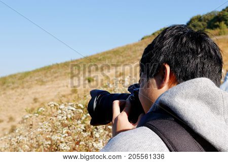 Young Asian tourist man taking a photo with dslr camera at Kew Mae Pan nature trail at Doi Inthanon Chaingmai Thailand