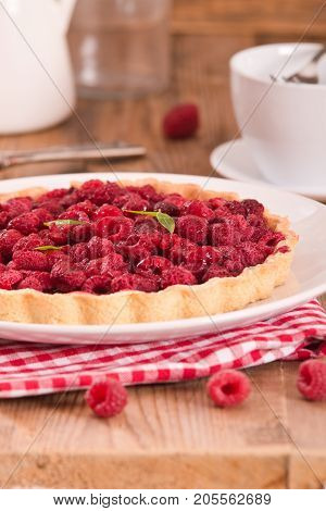 Raspberry tart with fresh rasperries in white bowl.