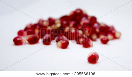 pomegranate seeds spilled on a white background